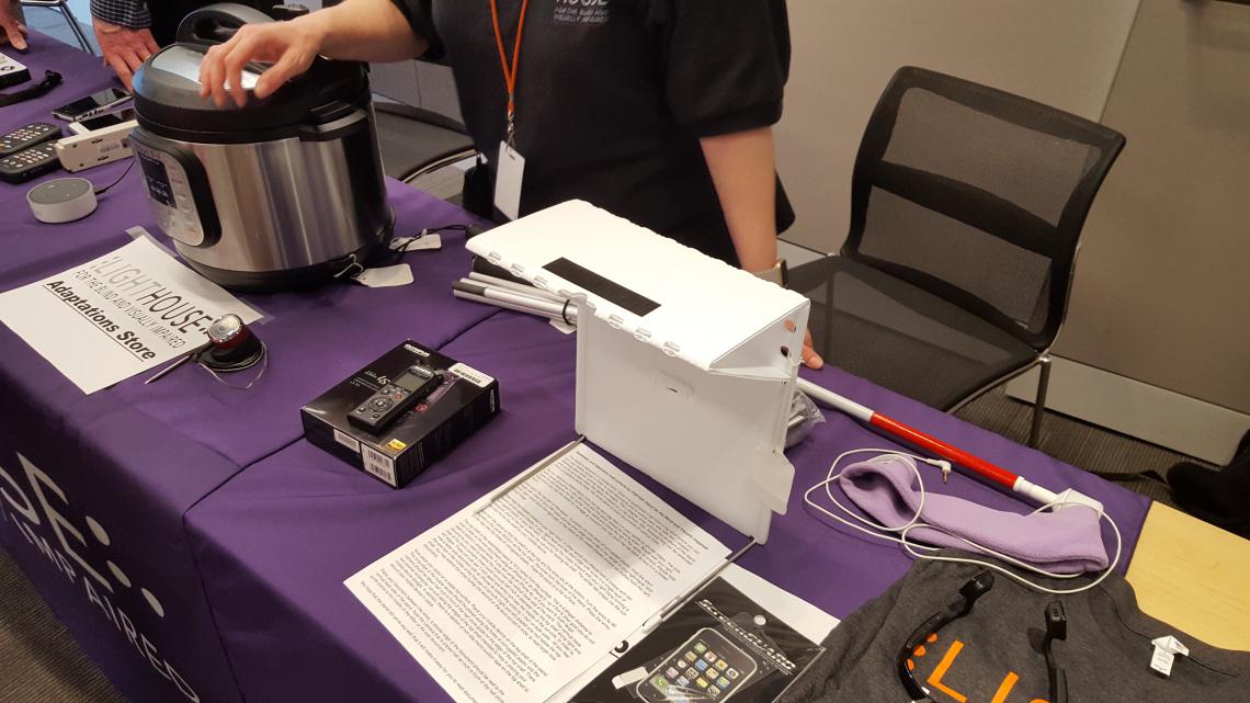 On the table is a mobile stand for a phone, a bluetooth pressure cooker, and an audio recorder